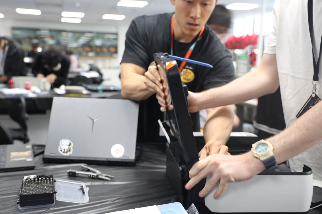 Two students assembling a hardware chassis at a workshop bench.